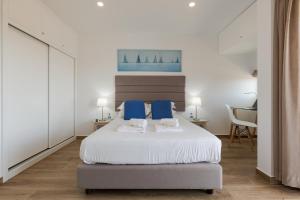 een slaapkamer met een groot wit bed met blauwe kussens bij FishermenApartments - Carcavelos 32 in Carcavelos