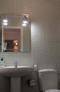 een badkamer met een wastafel, een toilet en een spiegel bij Lilo, Médano, Surf, Windsurf, Tenerife in Granadilla de Abona