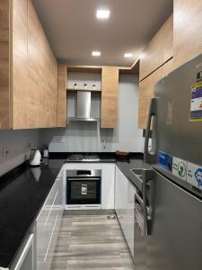 a kitchen with black counter tops and wooden cabinets at بنتهاوس ميدتاون ممنوع الزيارات للعزاب in Cairo
