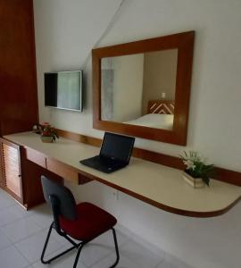 um quarto com uma secretária com um computador portátil e um espelho em Hotel Costa Azul em Cananeia