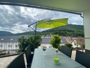 una mesa con una sombrilla amarilla y una copa de vino en Ferienwohnung Nuß en Annweiler am Trifels