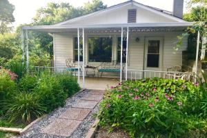 una casa con un porche con un banco y flores en Peaceful Garden Oasis - 3 miles to downtown!, en Asheville
