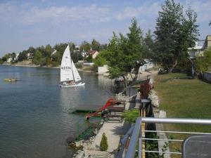 a sailboat on a river with a boat in the water at Apartmán s terasou in Senec