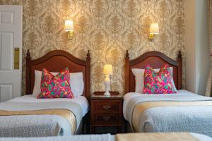 two beds with colorful pillows in a room at Egans House in Dublin