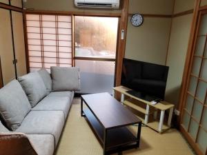 ein Wohnzimmer mit einem Sofa und einem TV in der Unterkunft Uminomanmaesou - Vacation STAY 65243v in Oda