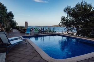 a swimming pool with chairs and a view of the water at Menurka - Port d'Addaia in Port d'Addaia