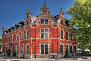 un grand bâtiment en briques rouges avec une tour d'horloge dans l'établissement Hotel zur Henne, à Naumbourg