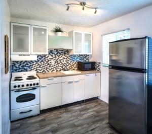 a kitchen with white cabinets and a stainless steel refrigerator at Park Shore Suites St Pete Beach in St Pete Beach