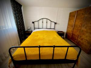 a bed with a yellow blanket on it in a room at Rynek_28 in Ciężkowice