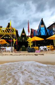 un groupe de bâtiments sur une plage avec des chaises et des parasols dans l'établissement Posada Tipiland la casa del Mono, à Playa Blanca