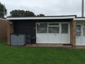 a garage with white doors and a grass yard at Headwards Retreat in Hemsby