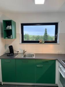 uma cozinha com armários verdes e uma janela em Ferienwohnung Klosterblick em Ühlingen-Birkendorf