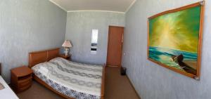 um quarto com uma cama com um quadro na parede em Ludmila guest house - гостевой дом "Людмила" em Odessa