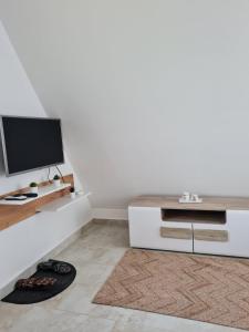 uma sala de estar com uma televisão e um armário branco em Apartmani Radaković em Vrdnik