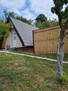 uma casa com uma cerca e uma árvore num quintal em Apartmani Radaković em Vrdnik