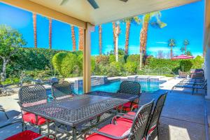 a patio with a table and chairs next to a swimming pool at Alluring Palm Desert Retreat in Palm Desert