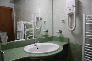 bagno con lavandino e specchio di Hotel Sir Orhideea a Bucarest
