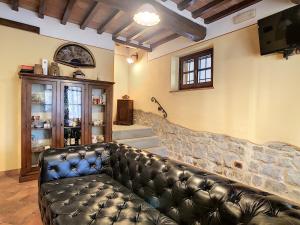 a leather couch in a room with a stone wall at Agriturismo Dominus Domenico in Cortona