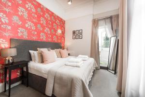 a bedroom with a bed and a red wall at Notting Hill Hotel by CAPITAL in London