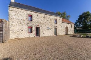 ein Steingebäude mit roten Fenstern auf einer Kieseinfahrt in der Unterkunft NOCNOC - Gîte du Vieux Pressoir, piscine chauffée et couverte in Campbon