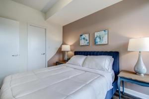 1 dormitorio con 1 cama blanca grande y 2 lámparas en The Benetton Suite - Square One 1 BR + Den + 1 Parking en Mississauga