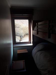 ein Fenster in einem Zimmer mit einem Bett und einem Felsen in der Unterkunft El Colorado Habitamar in El Colorado