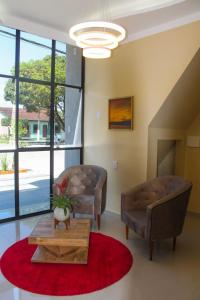 ein Wohnzimmer mit 2 Stühlen und einem Couchtisch in der Unterkunft HOTEL LISBOA in Capanema