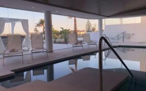 a pool with chairs and an umbrella next to a swimming pool at Luxury Apartment Diego - The View Fuengirola in Fuengirola