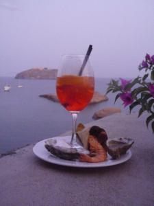 Ein Teller mit Essen und ein Getränk auf einem Tisch mit Blick auf das Meer in der Unterkunft Hotel Villa Iulia in Ventotene + 49 Fotos