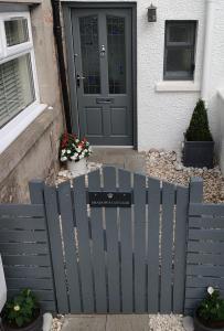 a blue fence in front of a house with a door at Shadow's Cottage situated in Fishertown, Nairn. in Nairn