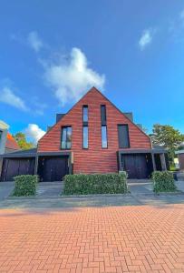 una casa de ladrillo rojo con ventanas y arbustos delante en Haus Kleemann K4, en Norderney