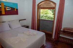 a bedroom with a bed with white sheets and a window at Planeta Macacos in Macacos +24 photos