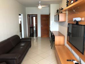a living room with a black couch and a kitchen at Apartamento Guarapari Luxo Frente para o Mar in Guarapari