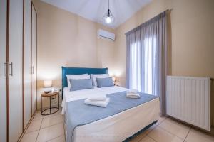 Un dormitorio con una cama azul y blanca y una ventana en Ελαιών apartments/Eleon apartments, en Korissia