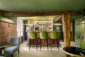 um bar com bancos verdes num quarto em The Relais Henley em Henley on Thames