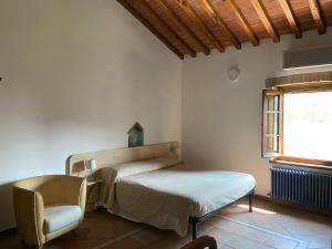 een slaapkamer met een bed, een stoel en een raam bij Bed & Breakfast Casale Gregoriano and Apartaments in San Gimignano