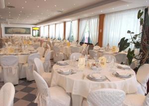 um salão de banquetes com mesas brancas e cadeiras brancas em Platani Hotel em Bolsena