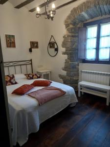 a bedroom with a bed and a stone wall at Hotel Doña Lola in Izarra