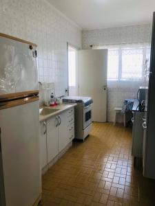 a kitchen with white appliances and a tile floor at Excelente Apartamento no Canto do Tortuga, praia da Enseada - Guarujá in Guarujá