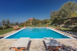 uma piscina com duas espreguiçadeiras e uma casa em Odina Agriturismo em Loro Ciuffenna