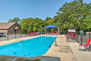 - une piscine avec des chaises rouges et un parasol bleu dans l'établissement Updated Cabin with Direct Lake Access and Pool!, à Lampe