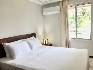 a bedroom with a large white bed with a window at Blue Marlin Cotovelo - Vista Vale - Reformado in Parnamirim