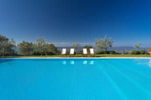 2 sillas sentadas junto a una piscina azul en Odina Agriturismo, en Loro Ciuffenna
