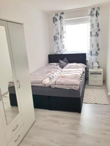 Schlafzimmer mit einem Bett, einem Spiegel und einem Fenster in der Unterkunft FeWo Rose - Mitten im Herz Goslar in Goslar