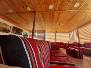 a room with a couch with red chairs and wooden ceilings at Petra Cabin Inn Hostel&Resturant in Wadi Musa