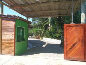 a green and wooden building with a wooden door at Suites Brejauva in Ubatuba