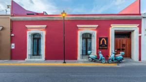 a red building with two scooters parked in front of it at Casa Naila Hotel Boutique in Oaxaca City