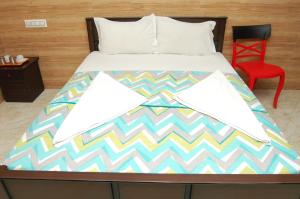 a bed in a room with a red chair at Adhi Residency in Kanchipuram