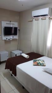 a hotel room with a bed and a flat screen tv at Pousada Pingo do Meio Dia in Mossoró
