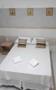 a white bed with two pillows on top of it at Pousada Pingo do Meio Dia in Mossoró